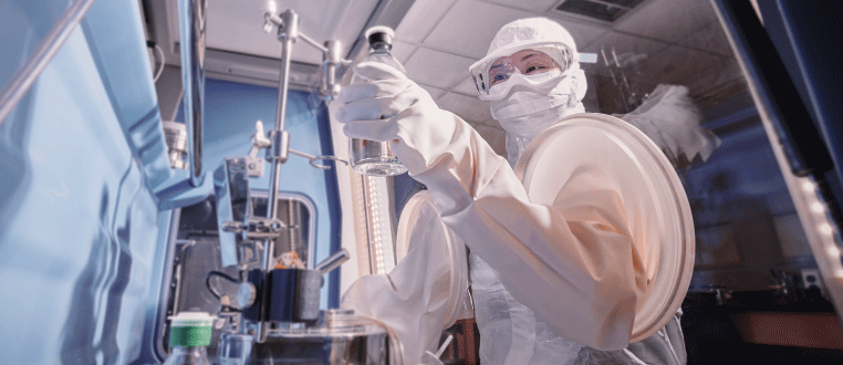 Image of a cleanroom worker in full protective clothing handling a product in a sterile cleanroom work setting