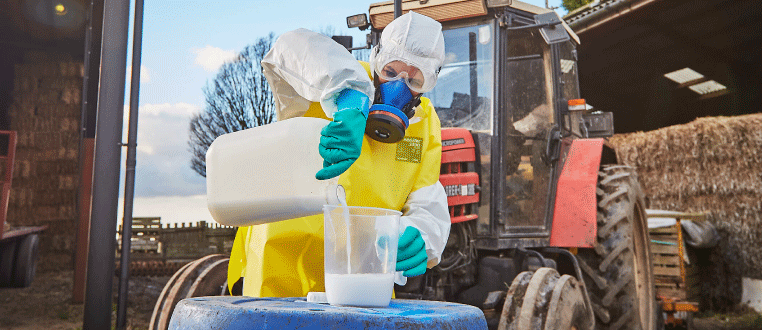 Image of a worker in a full protective chemical suit handling potentially hazardous chemical in an industrial setting